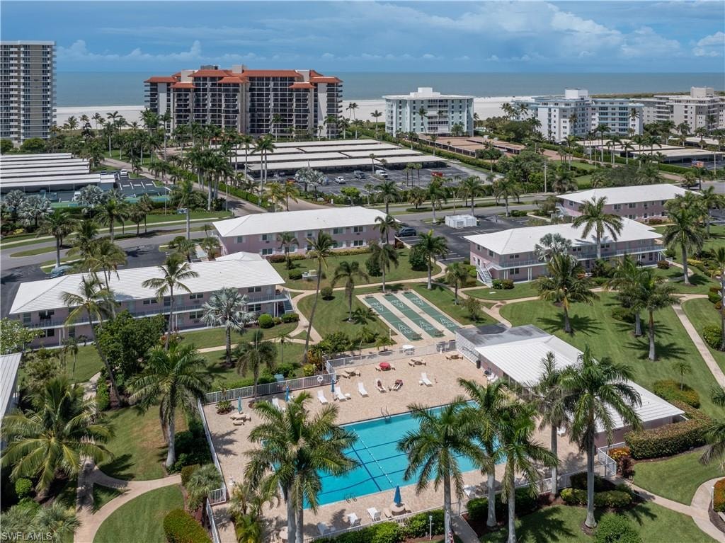 Aerial perspective showcasing multiple residential buildings, a swimming pool, and recreational courts
