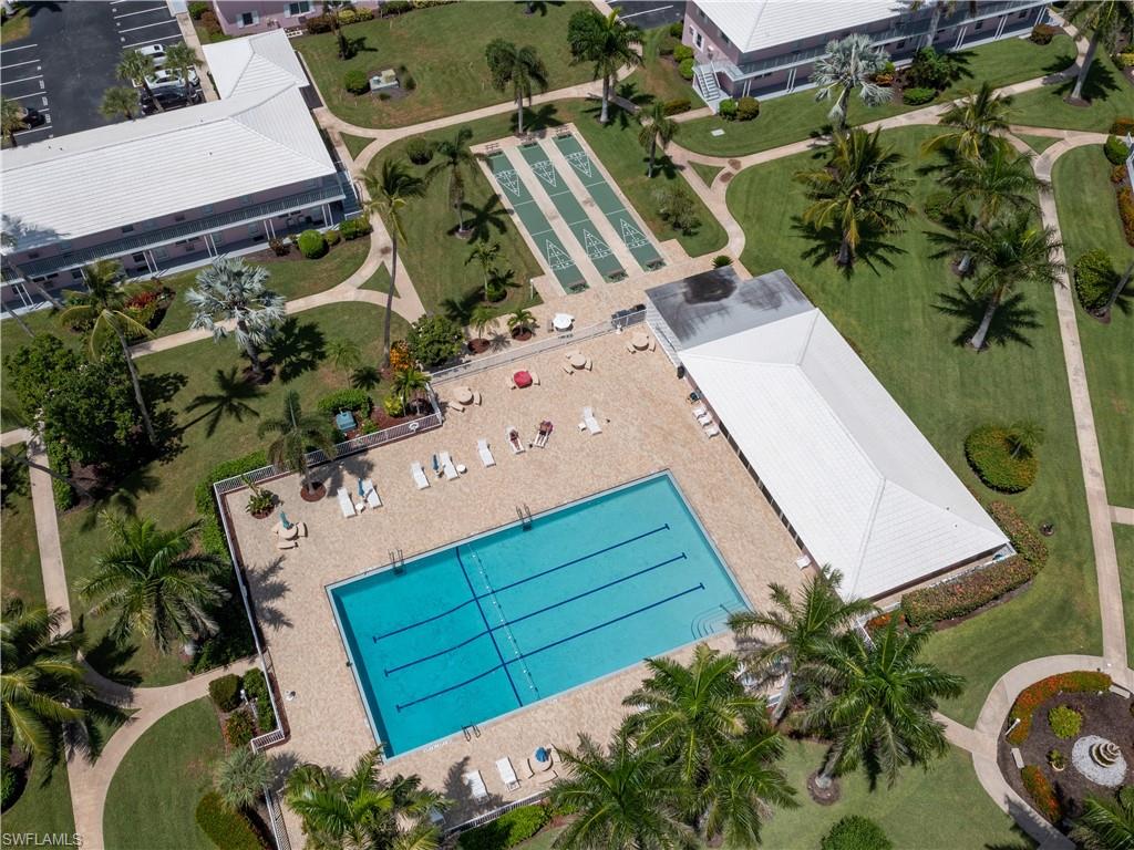 Community swimming pool with surrounding paver deck, shuffleboard courts, and multiple residential buildings