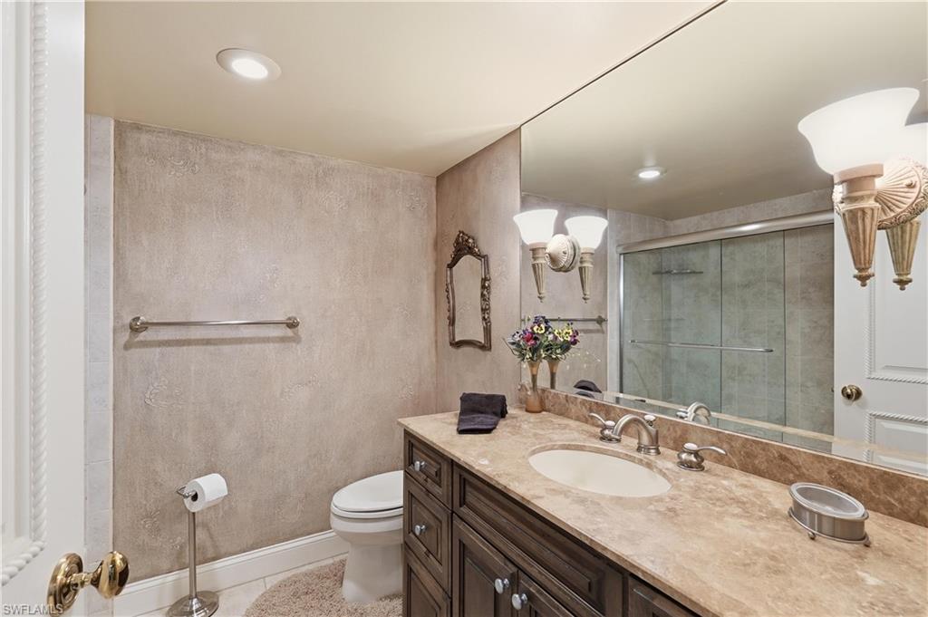 Bathroom featuring a vanity with a stone countertop, an undermount sink, and dark wood cabinetry