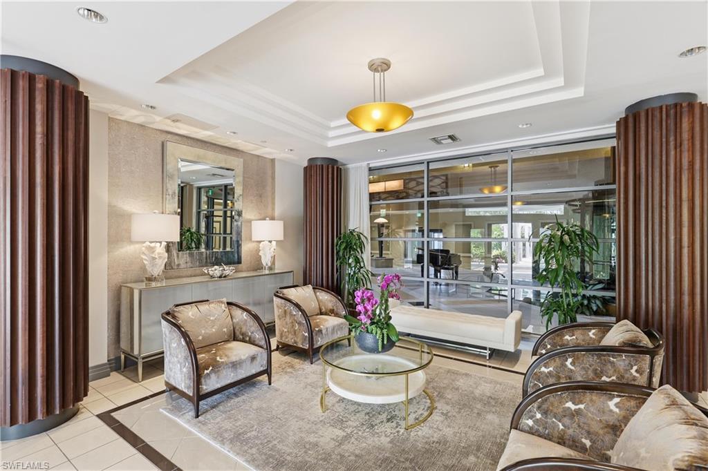 Lobby seating area featuring fluted wood columns, recessed lighting, and a tray ceiling