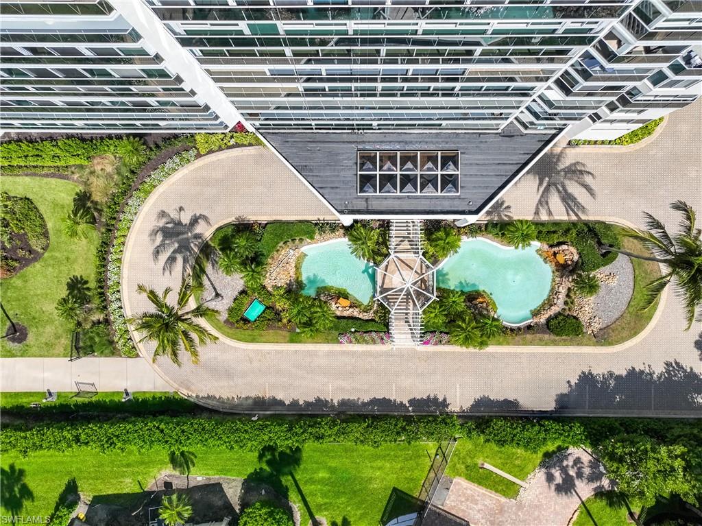 Circular driveway entrance featuring tropical landscaping and a two-tiered water feature with a pedestrian bridge
