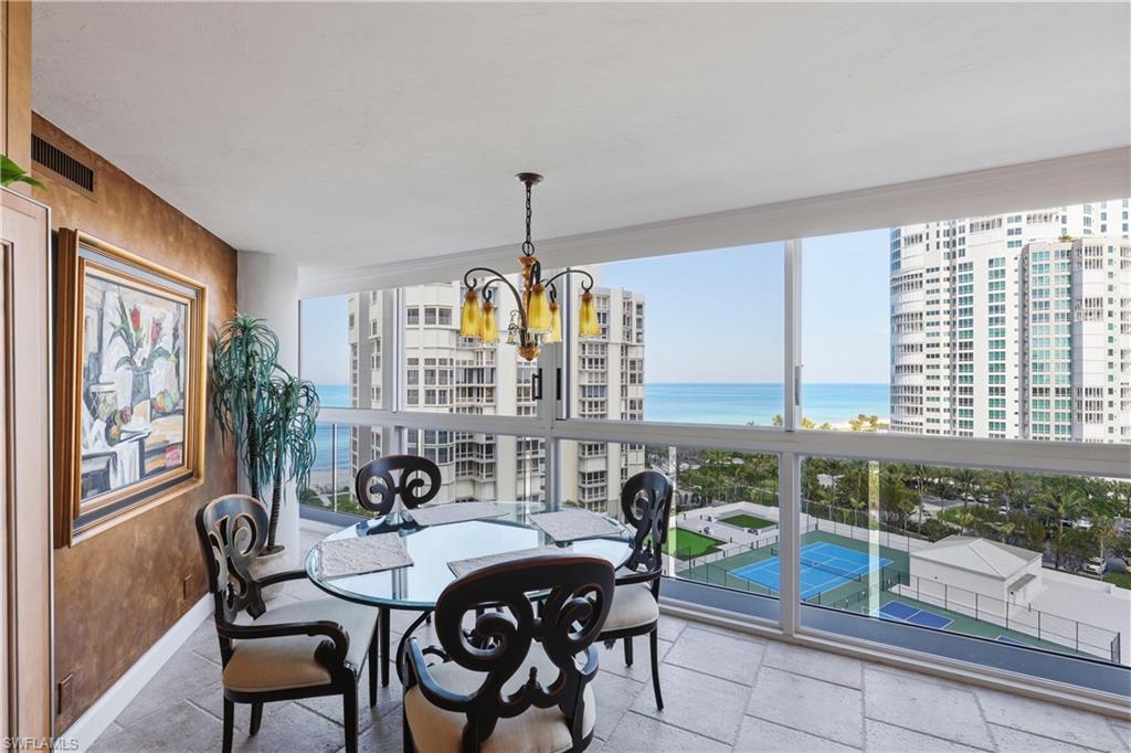 Dining area featuring expansive floor-to-ceiling windows, travertine-style tile flooring, and a decorative chandelier