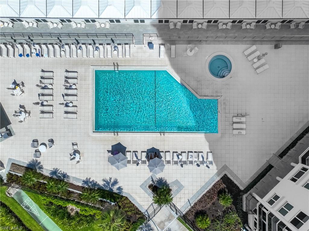 Resort-style pool area featuring a large swimming pool, circular spa, and extensive paved deck