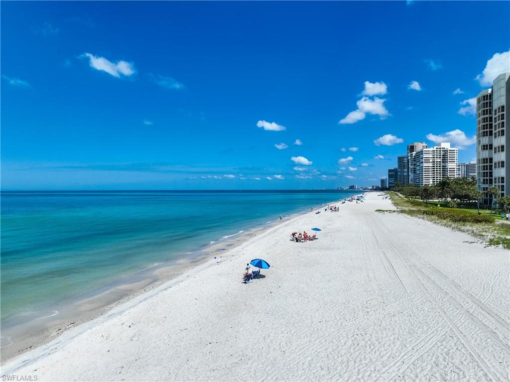 Expansive white sand beach with turquoise waters and a clear blue sky