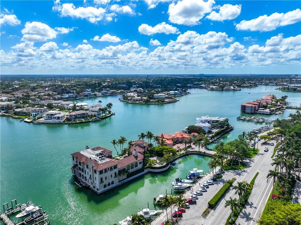 Waterfront property featuring a private boat dock, Mediterranean-style architecture, and lush palm landscaping
