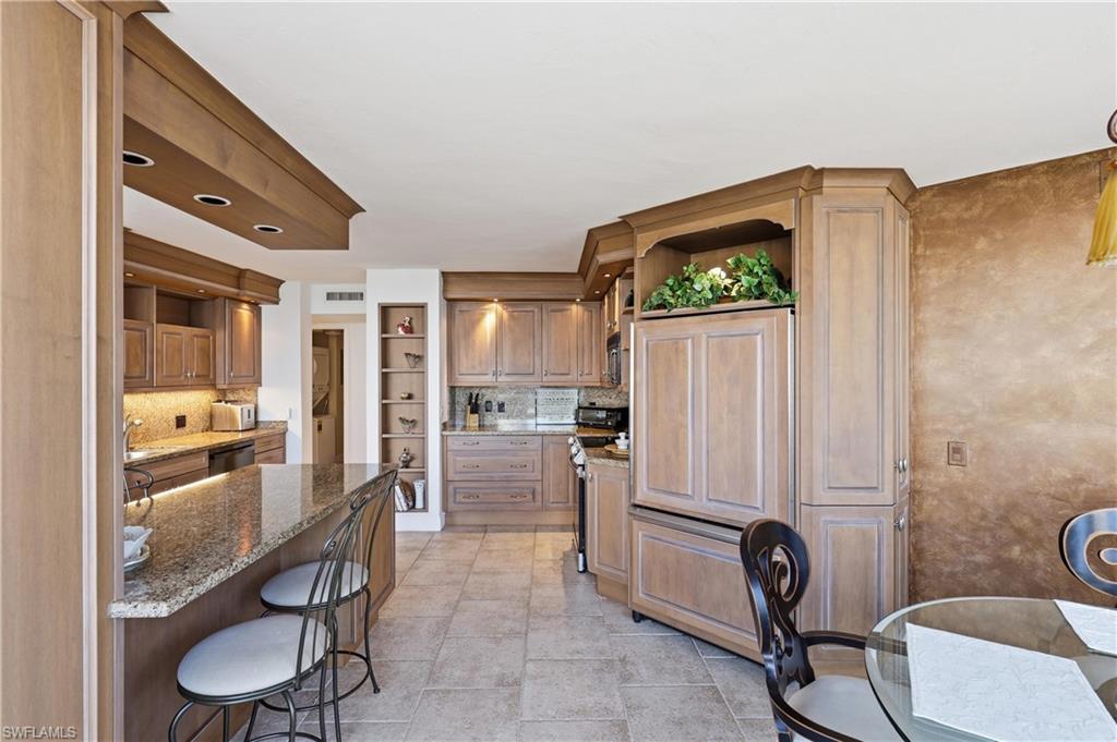 Kitchen featuring extensive cabinetry, granite countertops, tile flooring, built-in shelving, and recessed lighting