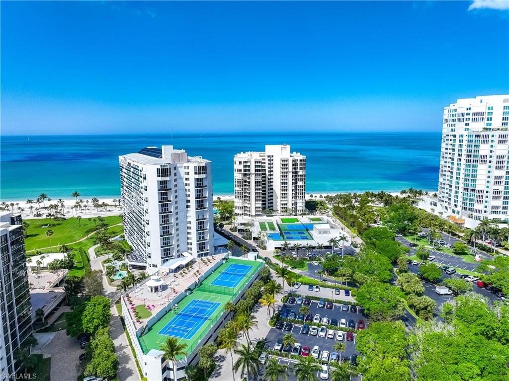 Coastal property featuring multiple high-rise buildings, tennis courts, and beachfront access