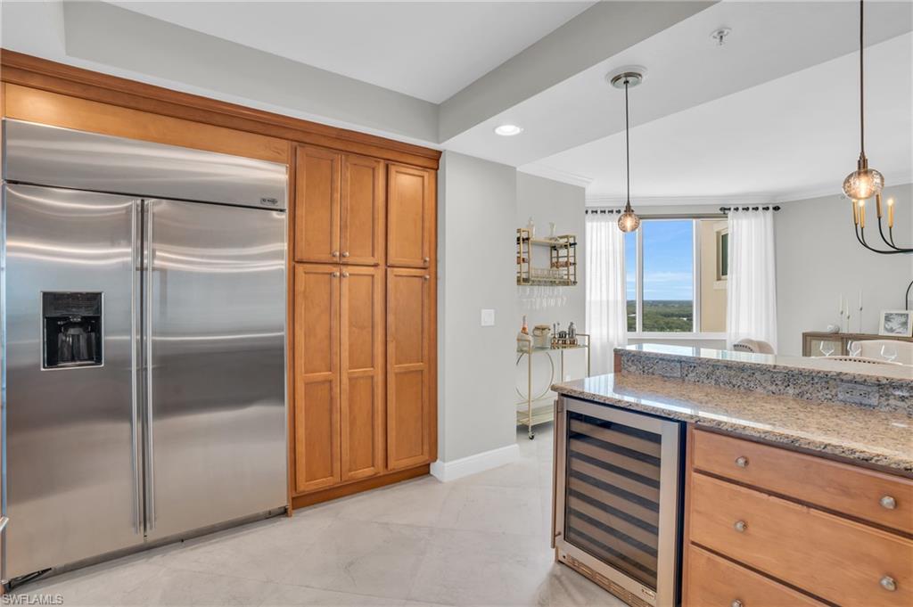 Kitchen with wine cooler, light stone counters, stainless steel built in refrigerator, and pendant lighting
