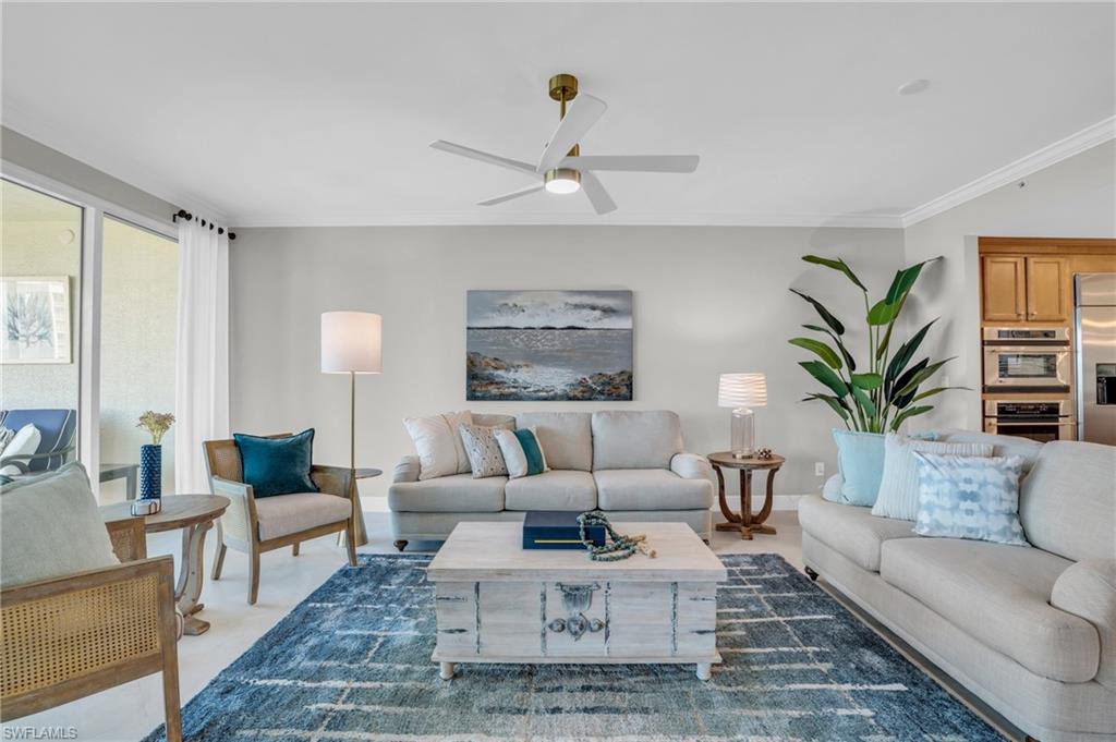 Carpeted living room with ceiling fan and ornamental molding