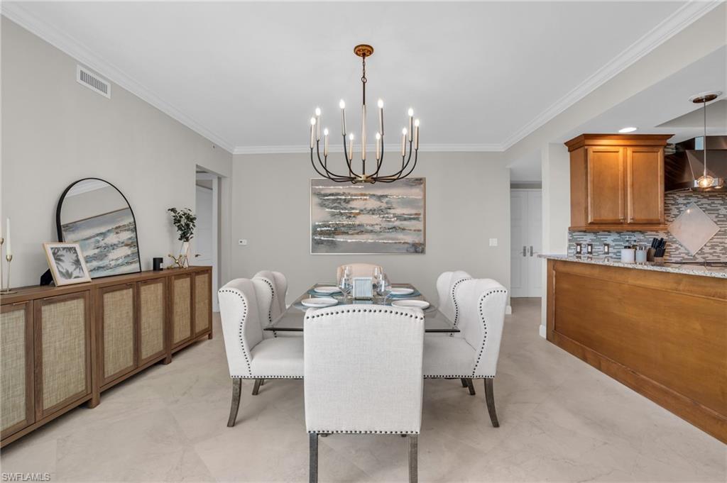 Dining room with ornamental molding, an inviting chandelier, and light tile flooring