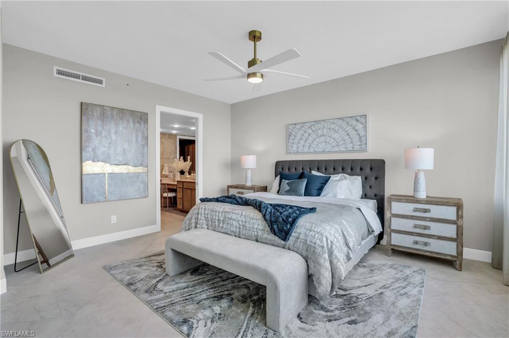 Bedroom featuring ceiling fan, light tile flooring, and ensuite bath