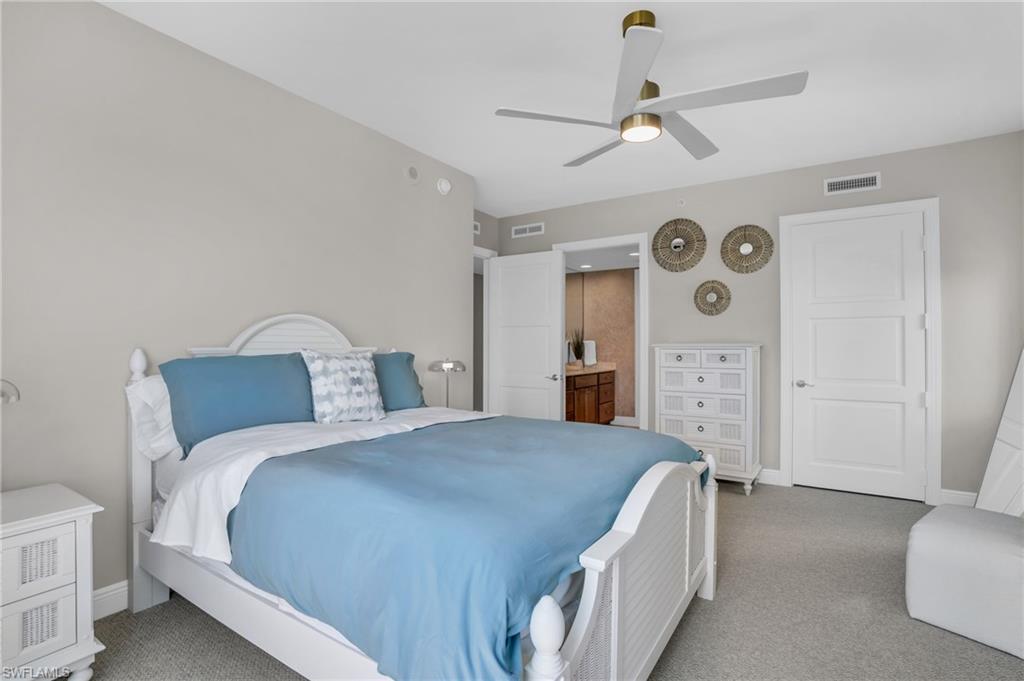 Carpeted bedroom with ensuite bathroom and ceiling fan
