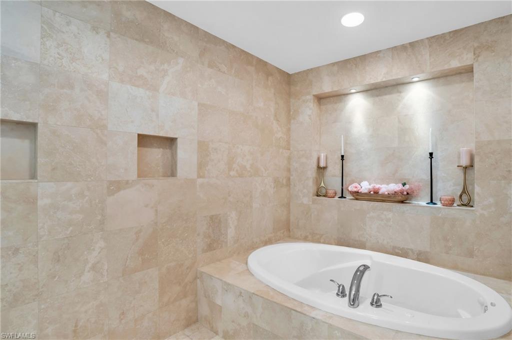 Bathroom featuring tiled bath and tile walls
