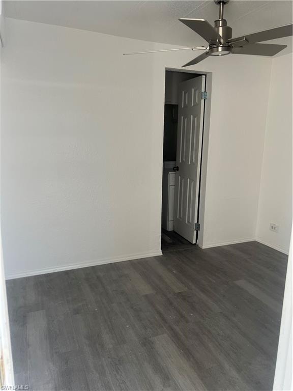 Unfurnished room featuring dark wood-type flooring, baseboards, and ceiling fan