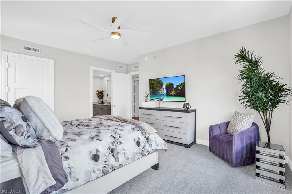 Bedroom with light carpet, connected bathroom, and ceiling fan