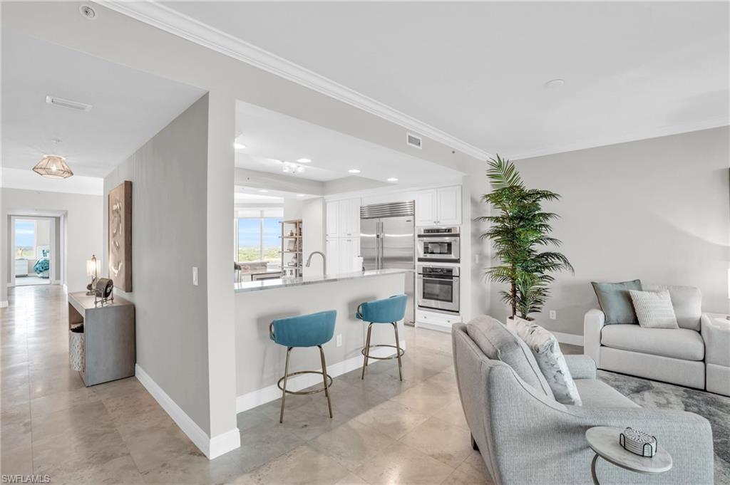 Living room featuring sink, light tile patterned floors, and ornamental molding