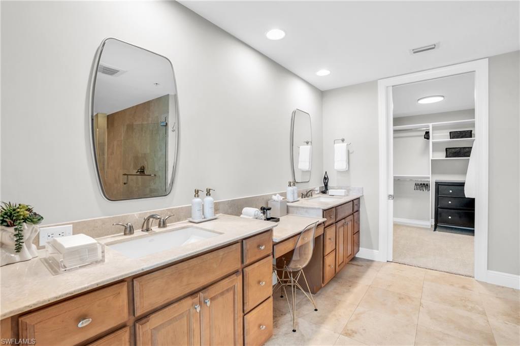 Bathroom with tile patterned flooring, walk in shower, and dual bowl vanity