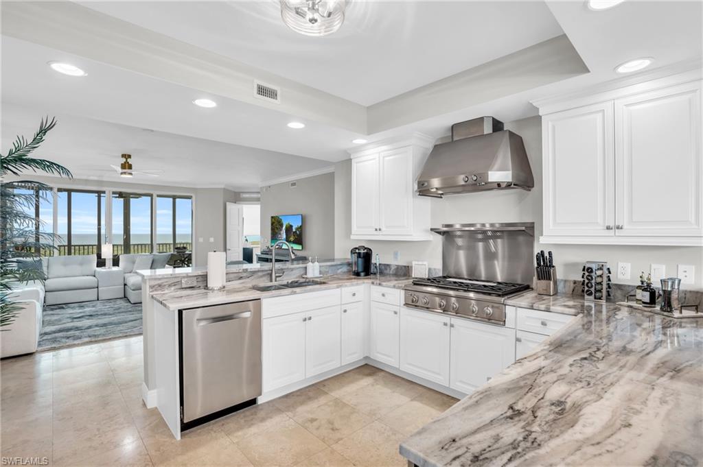 Kitchen with ceiling fan, wall chimney exhaust hood, sink, appliances with stainless steel finishes, and kitchen peninsula