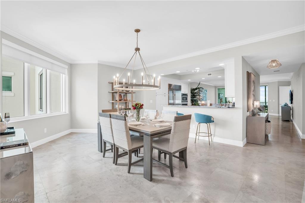 Dining room with ornamental molding, a notable chandelier, and light tile patterned floors