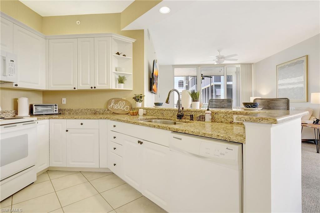 Kitchen featuring kitchen peninsula, white cabinets, white appliances, sink, and light colored carpet