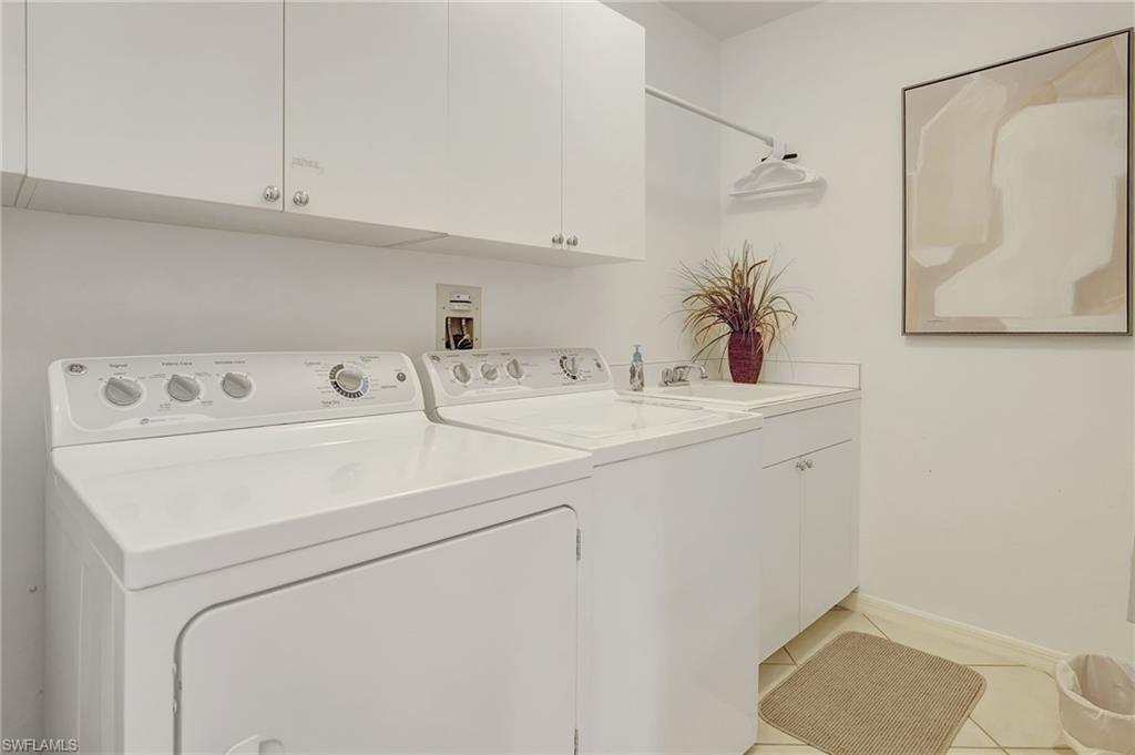Laundry room with light tile patterned flooring, sink, cabinets, and separate washer and dryer
