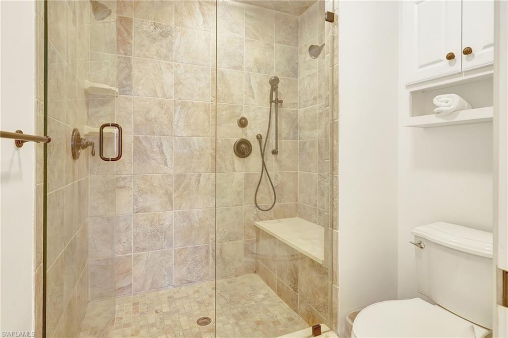 Bathroom featuring a shower with door and toilet