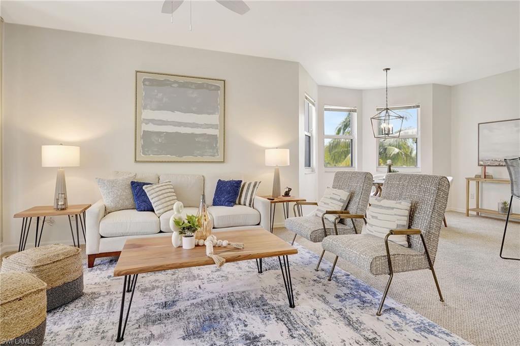 Carpeted living room featuring ceiling fan with notable chandelier