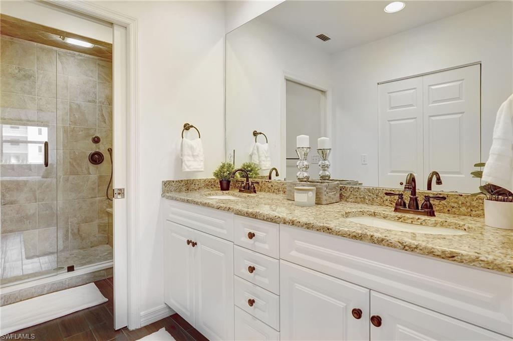 Bathroom featuring tiled shower and dual vanity