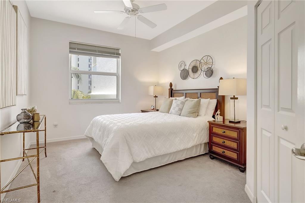 Carpeted bedroom with ceiling fan and a closet