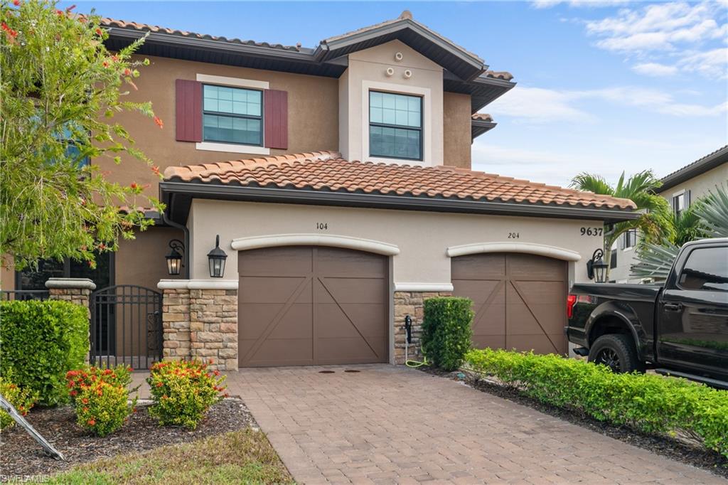 View of front facade with decorative driveway, stone siding, and stucco siding
