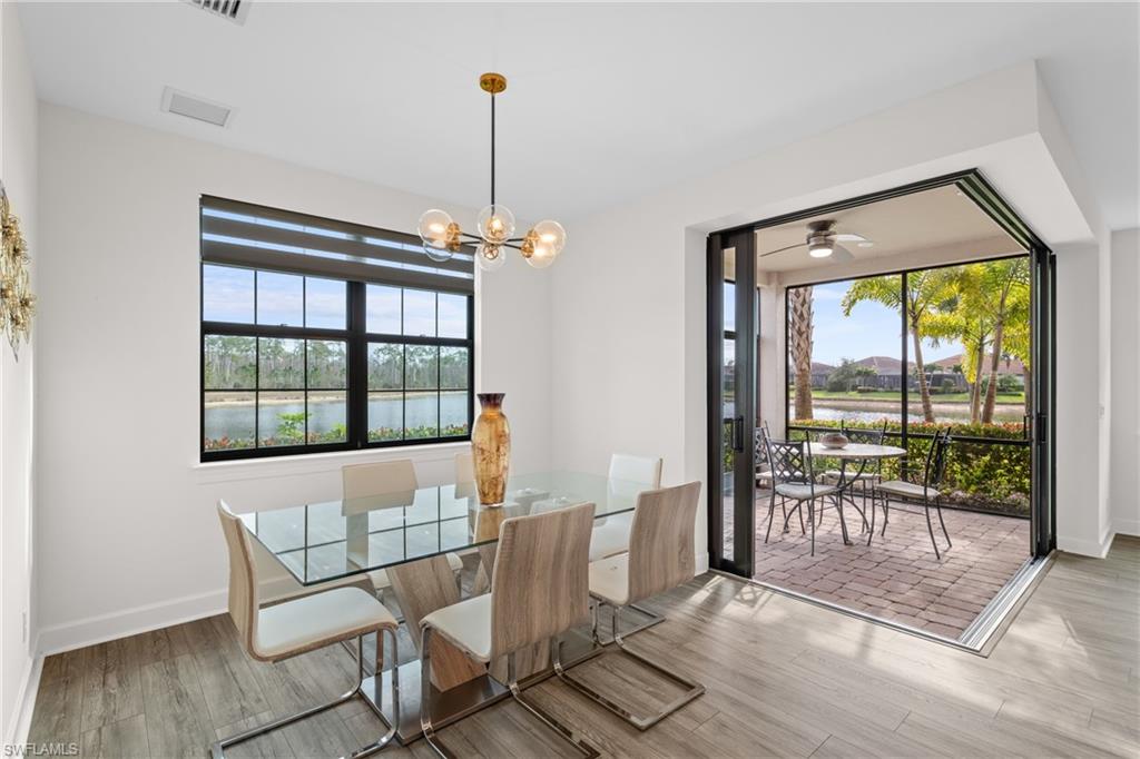 Dining room featuring a water view, a chandelier, wood finished floors, and a ceiling fan