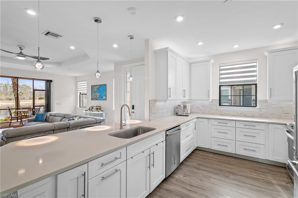 Kitchen featuring decorative light fixtures, open floor plan, white cabinets, recessed lighting, and light stone countertops