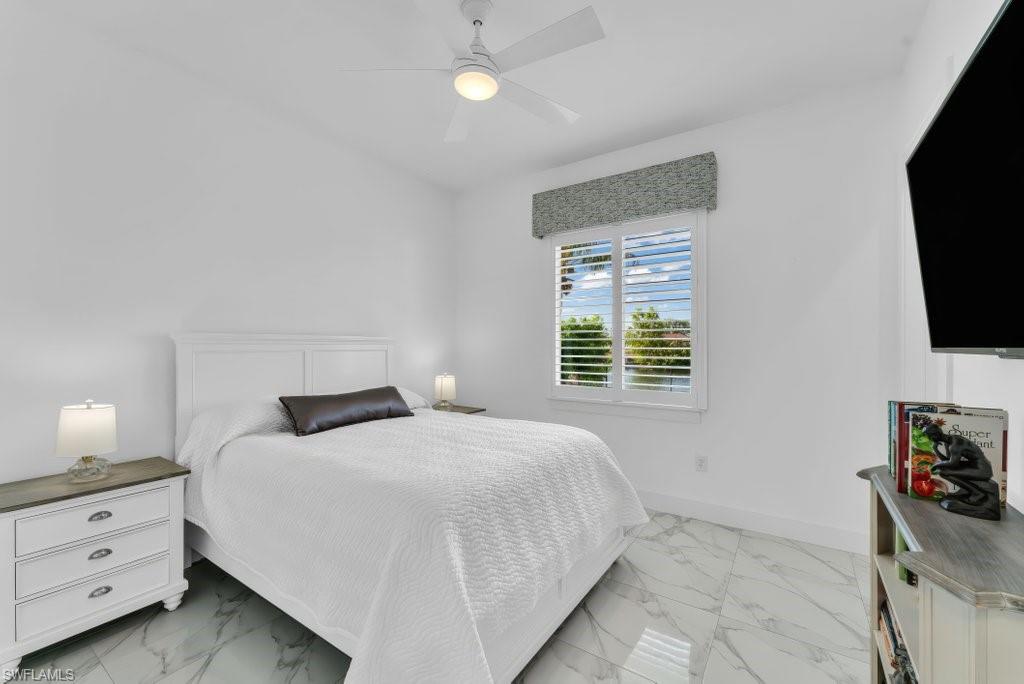 Bedroom featuring white walls and a white ceiling fan with integrated lighting