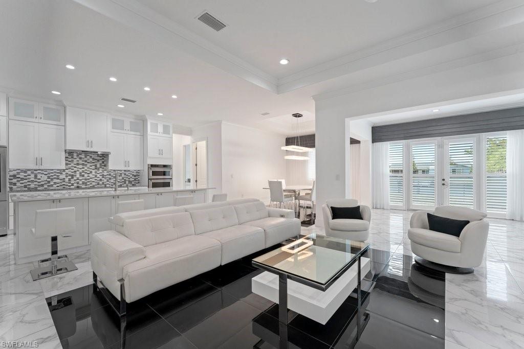Open-concept living space featuring a modern kitchen with white cabinetry, a mosaic tile backsplash, and stainless steel appliances