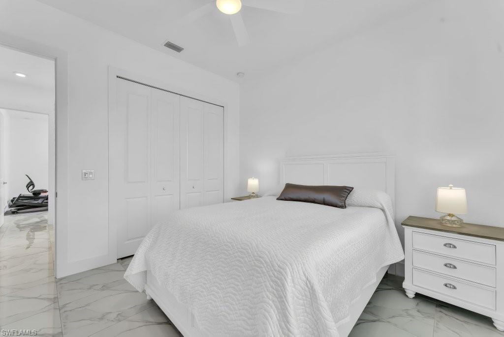 Bedroom featuring white walls, large bi-fold closet doors, and white marble-look flooring