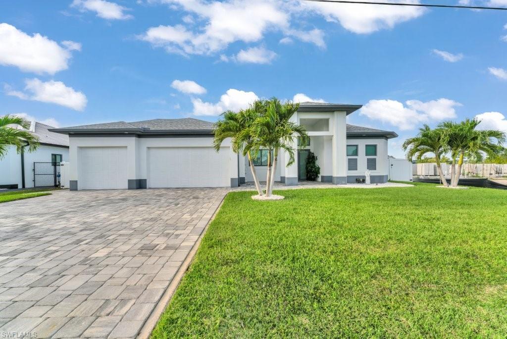 Modern exterior featuring a white stucco finish with dark gray trim accents and a paver driveway