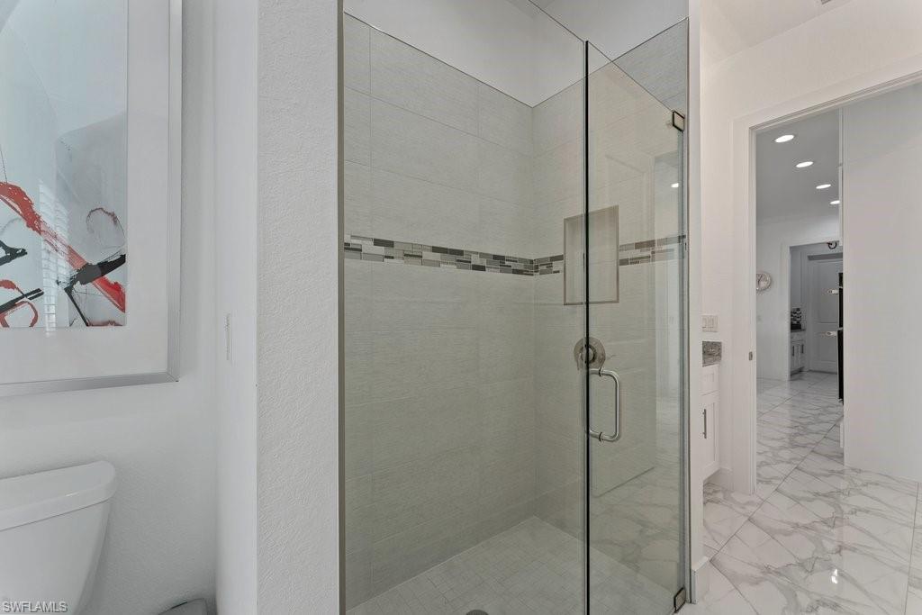 Glass-enclosed shower with subway tile surround, accent mosaic band, and built-in niche