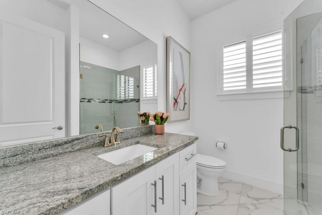 Bathroom featuring a vanity with a stone countertop, an undermount sink, and brushed nickel fixtures