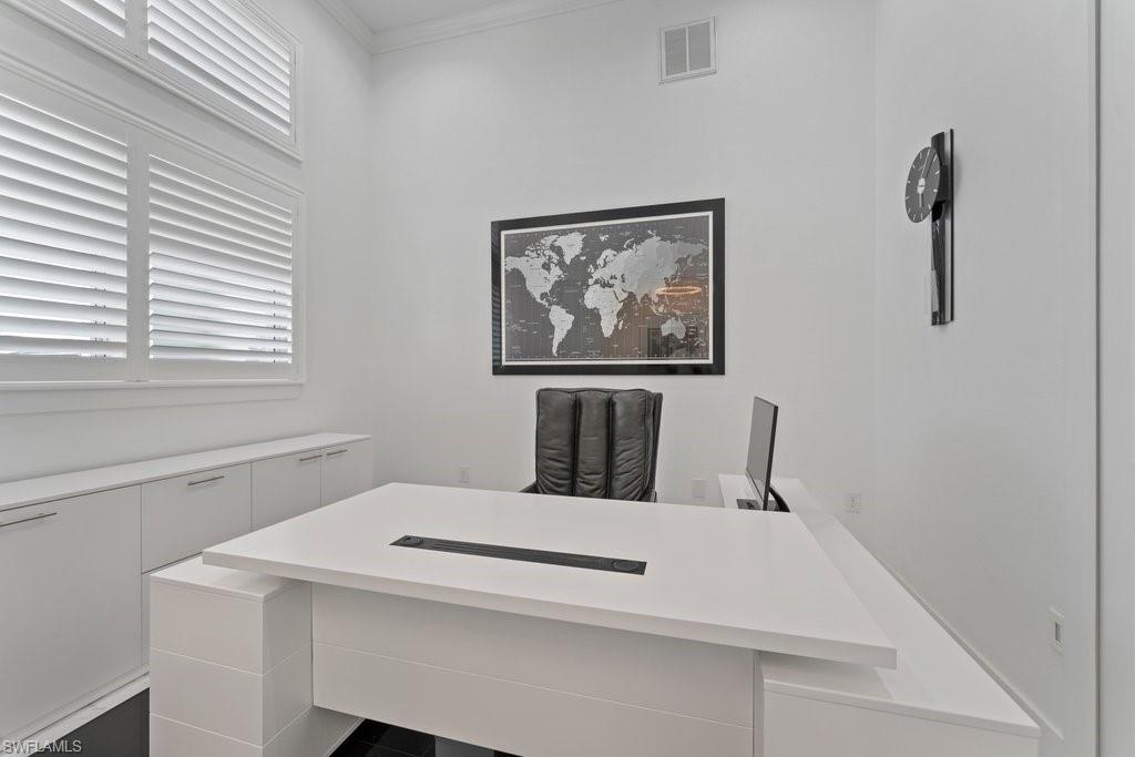 Dedicated workspace featuring high ceilings, white walls, and built-in white cabinetry with chrome hardware
