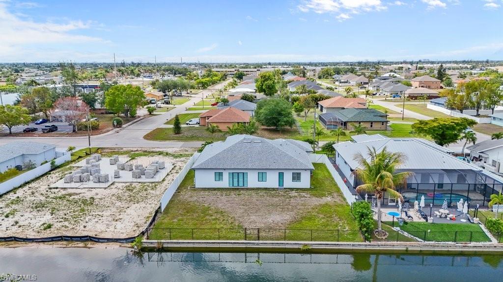 Waterfront property featuring a newly constructed residence, a spacious lot for future development, and a concrete foundation with building materials