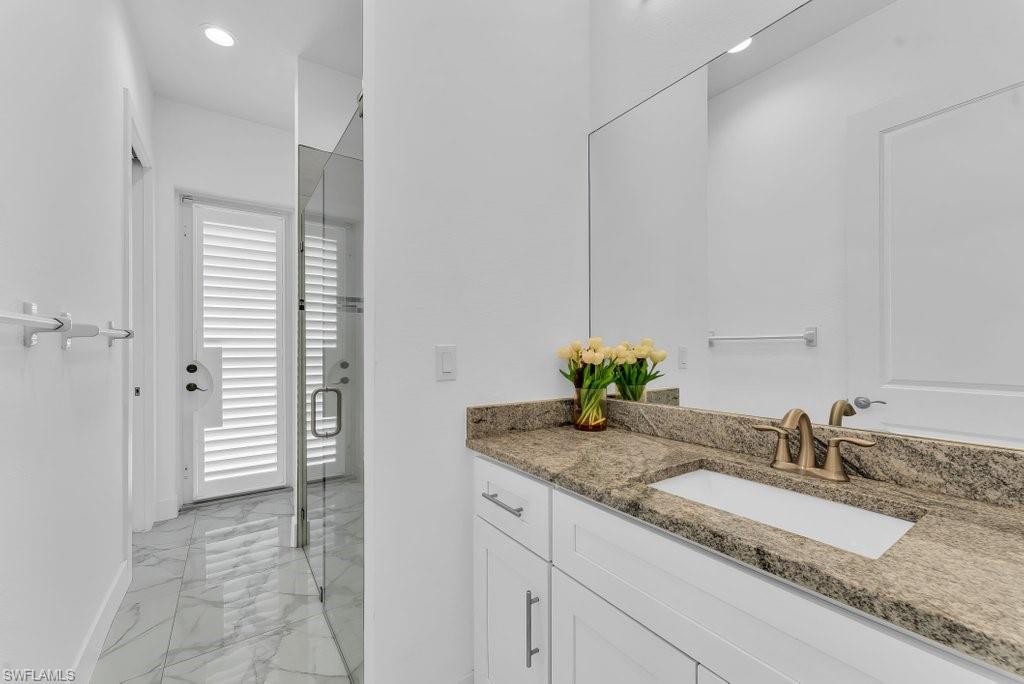 Contemporary bathroom featuring an integrated sink with a granite countertop, brass-finish faucet, and a large wall-mounted mirror