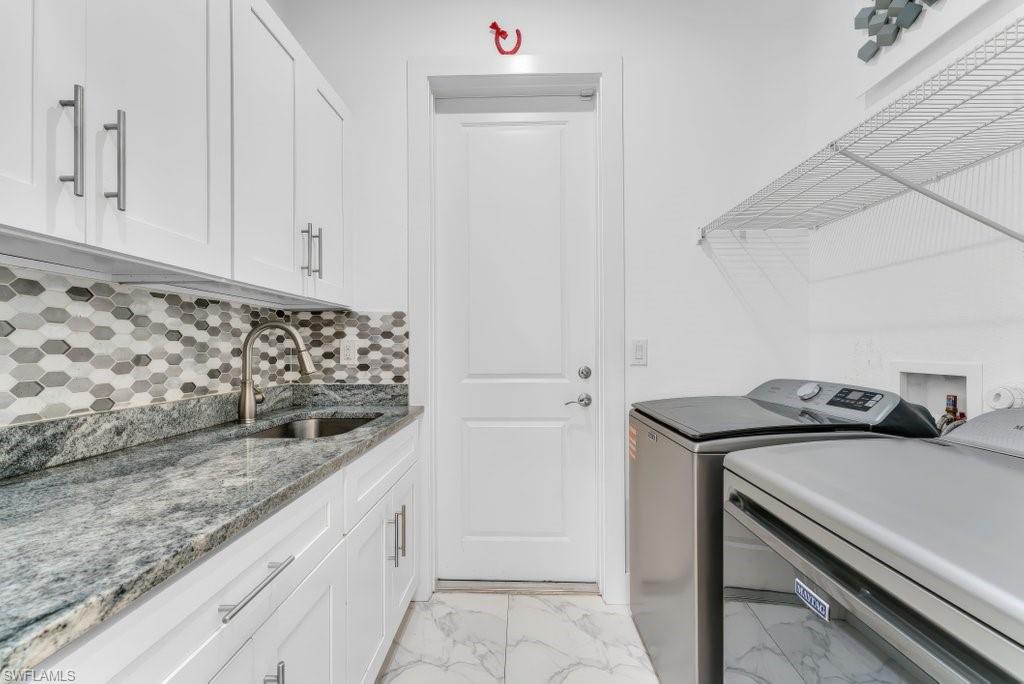 Laundry room featuring white cabinetry, a large sink, stone countertop, hexagon tile backsplash, and tile flooring
