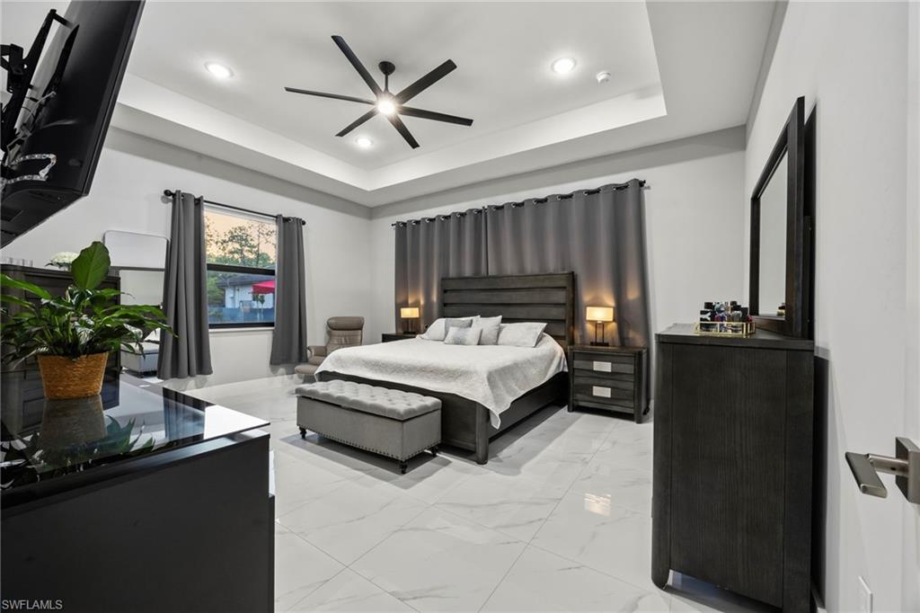 Primary bedroom featuring recessed lighting, a tray ceiling, and a contemporary ceiling fan
