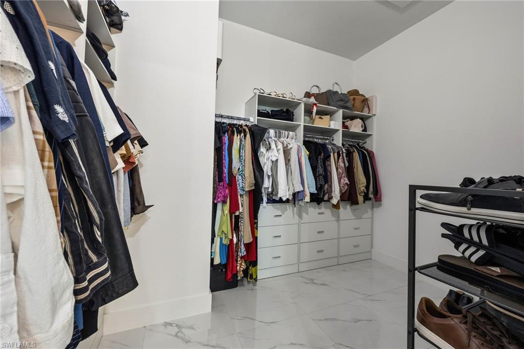 Walk in closet featuring white cabinetry, built-in shelving, hanging rods, and drawer storage