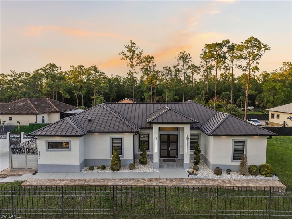 Contemporary single-story residence with a dark metal roof and light stucco exterior