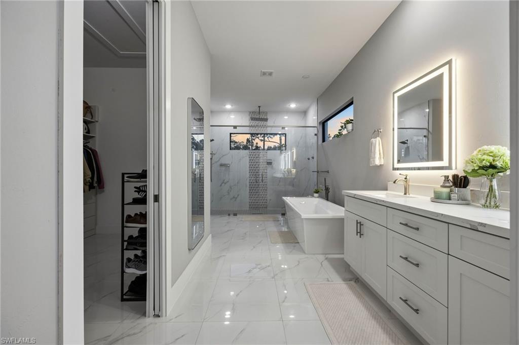 Primary bathroom featuring a freestanding soaking tub, and a large glass-enclosed shower with contrasting tile accents