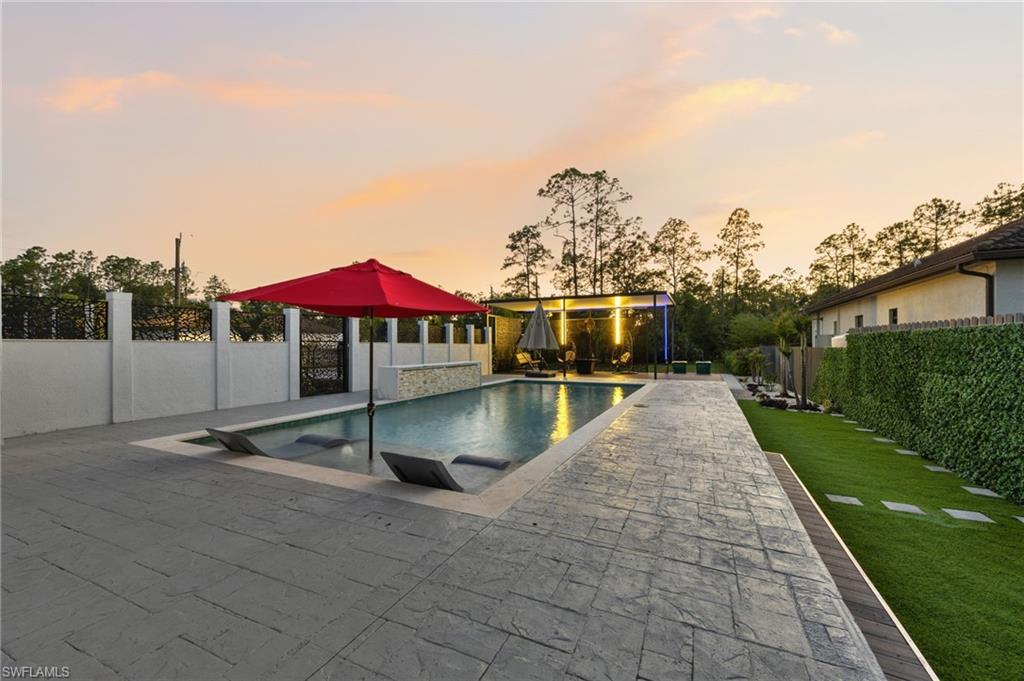 Resort-style pool area featuring stamped concrete decking, sun shelf with in-pool loungers