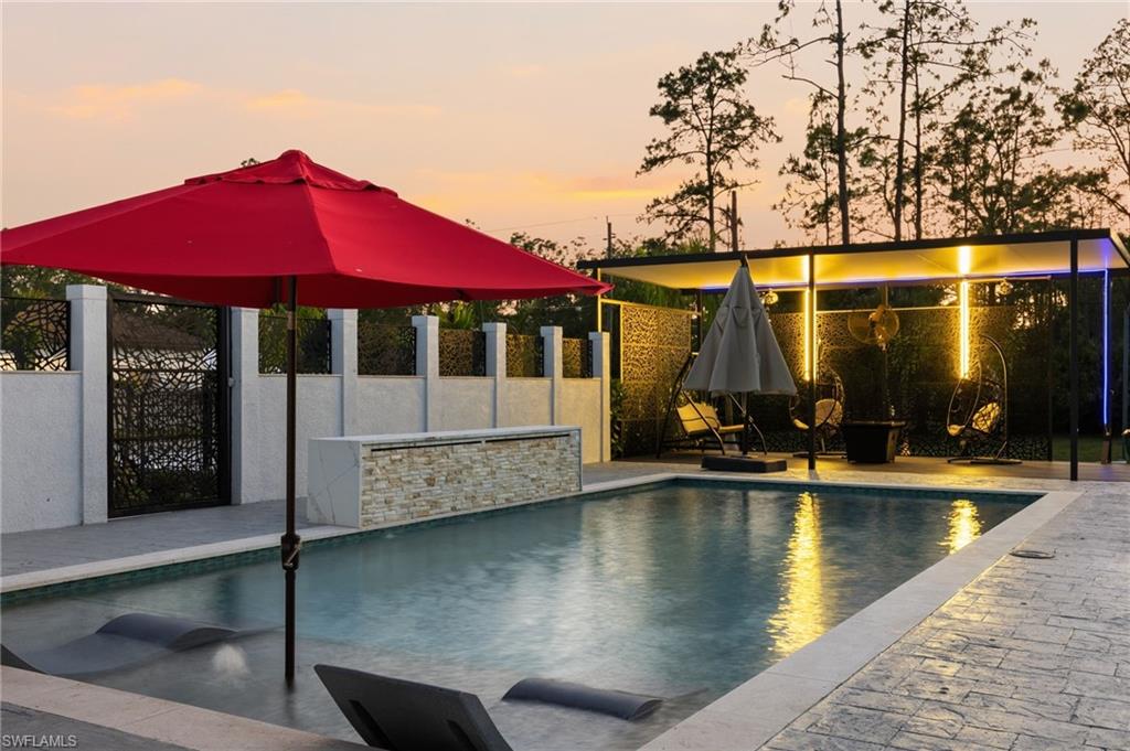 Outdoor swimming pool with built-in lounge chairs and a stacked stone water feature