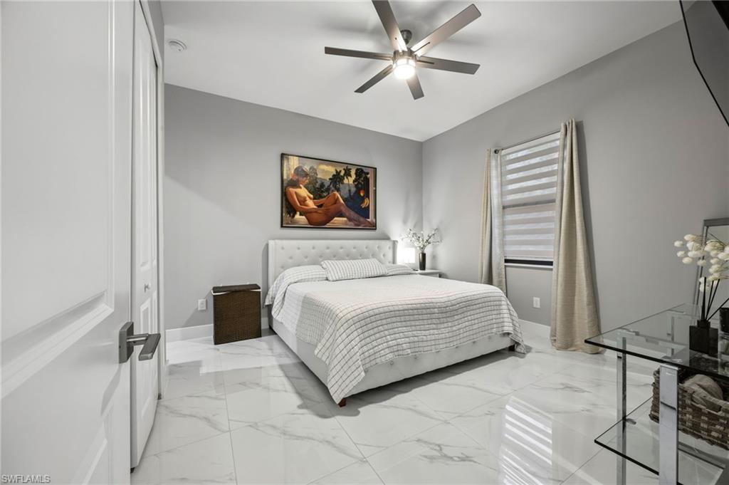 Spacious room featuring large format tile flooring, a modern ceiling fan, and a window with blinds and drapes