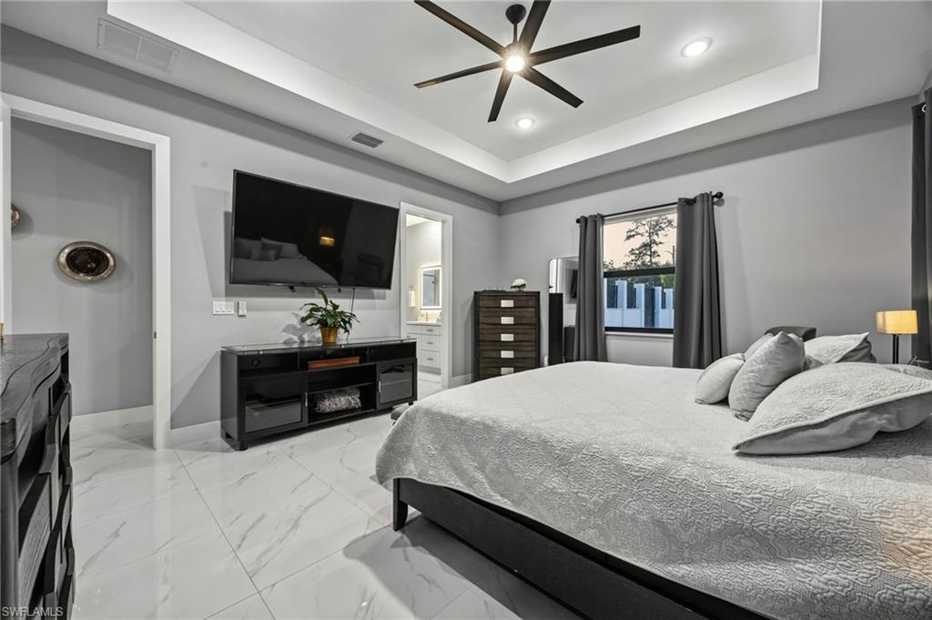 Primary bedroom featuring recessed lighting, a tray ceiling, and a contemporary ceiling fan